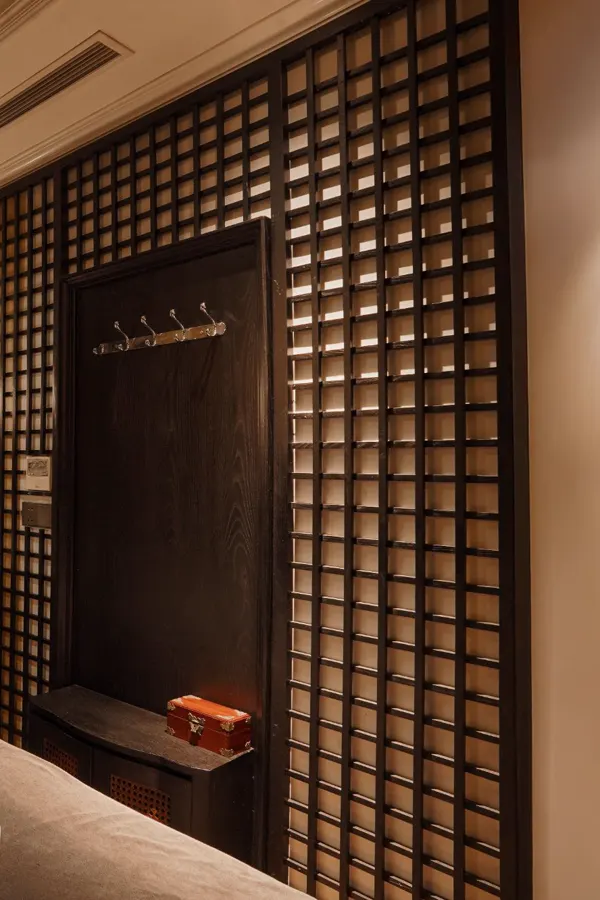 Lattice wall with coat hooks and a lacquered box beside a treatment bed