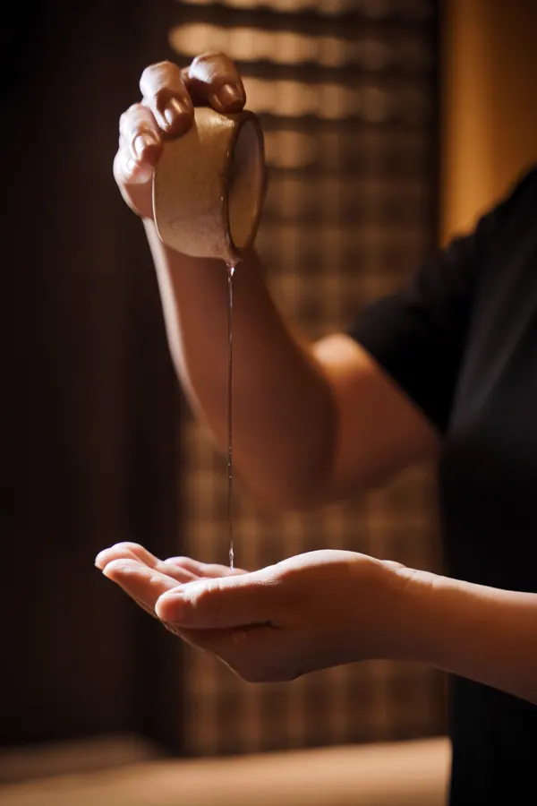 Therapist pouring warm massage oil into her palm