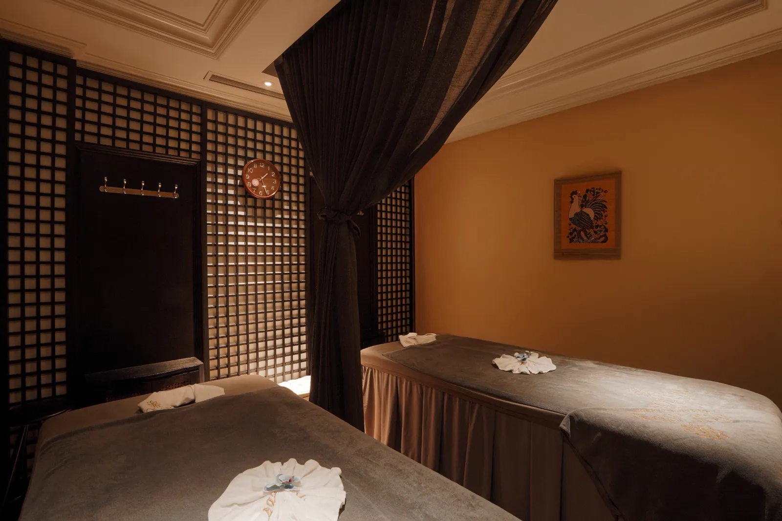 Twin treatment room at Sol Spa Hanoi with dark wooden lattice screens and a draped curtain