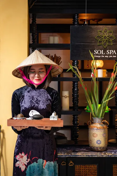 Spa host in ao dai and conical hat holding a welcome tray